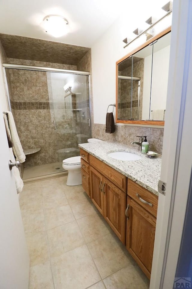 bathroom featuring a stall shower, tile patterned flooring, vanity, and toilet