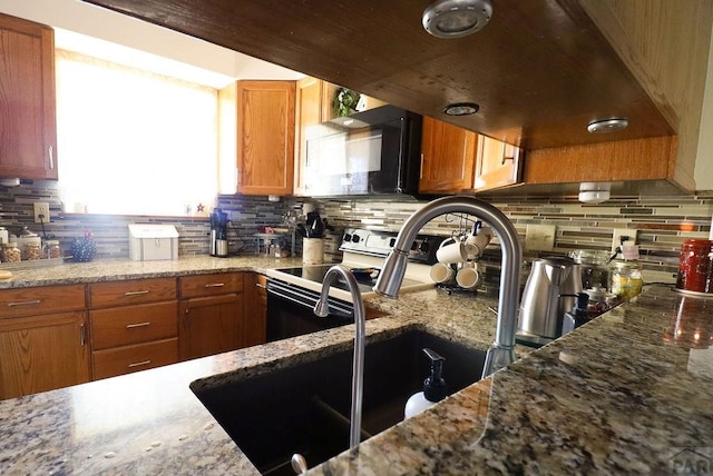 kitchen featuring black microwave, tasteful backsplash, range with electric stovetop, and brown cabinetry