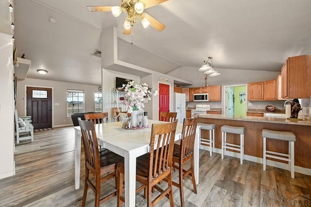 dining space featuring ceiling fan, wood finished floors, visible vents, baseboards, and vaulted ceiling