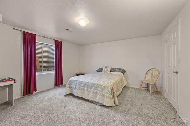 bedroom with carpet, visible vents, and a textured ceiling