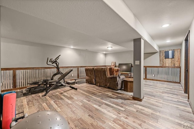 workout area featuring a textured ceiling, light wood-style flooring, and recessed lighting