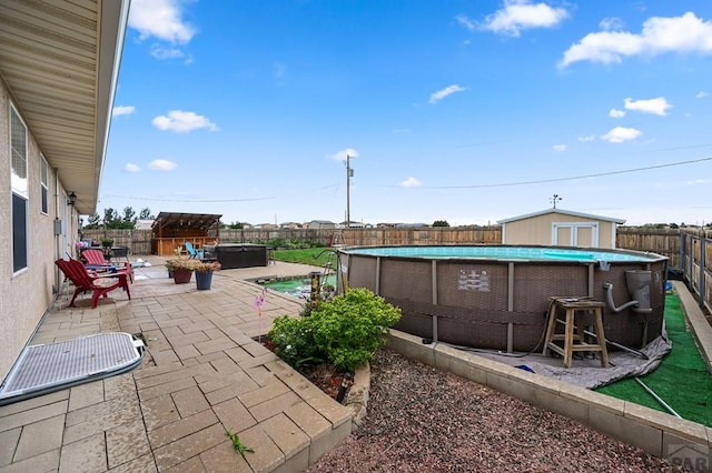 view of patio / terrace featuring a hot tub, a fenced backyard, a fenced in pool, and an outbuilding