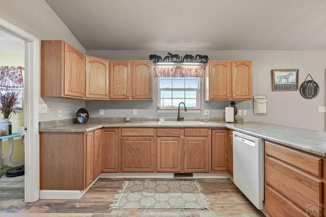 kitchen with dishwashing machine, light wood-style flooring, a sink, and light countertops