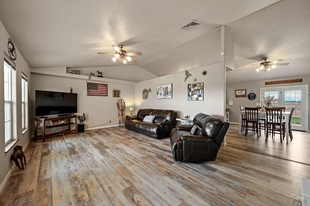 living area featuring lofted ceiling, ceiling fan, visible vents, and wood finished floors