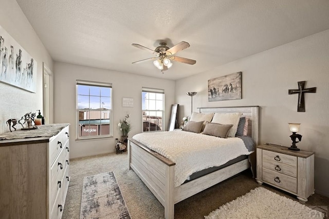 bedroom with carpet, ceiling fan, and a textured ceiling