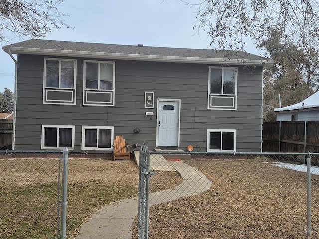 raised ranch with a front lawn and fence