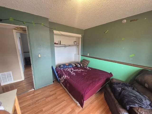 bedroom featuring a textured ceiling, light wood-type flooring, and visible vents