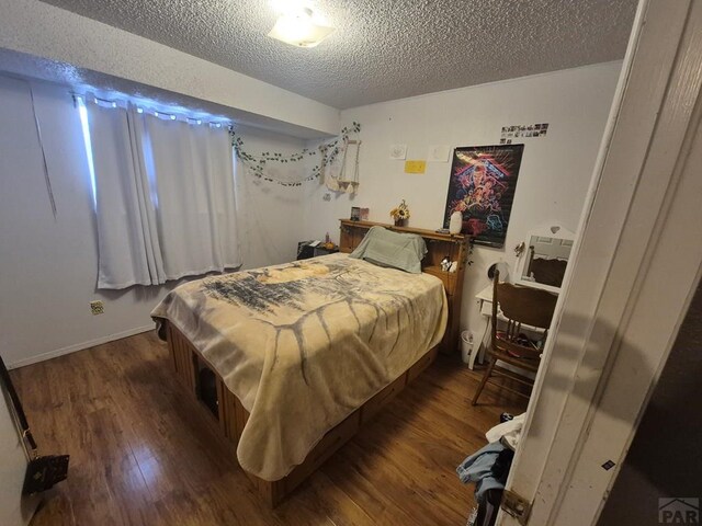 bedroom with dark wood finished floors and a textured ceiling