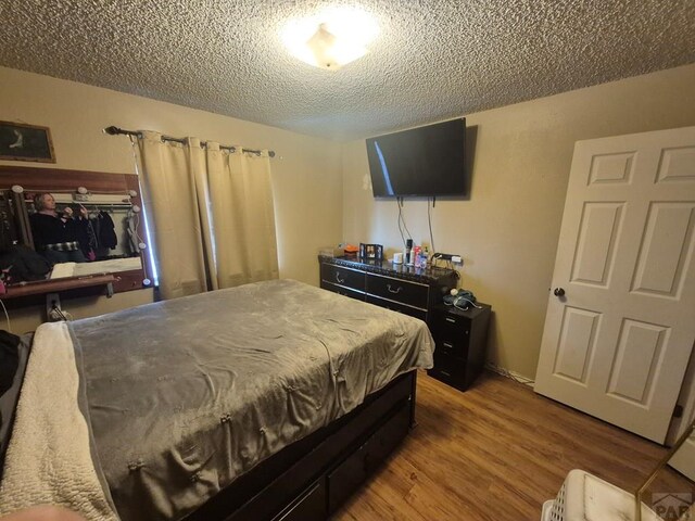 bedroom with a textured ceiling and wood finished floors