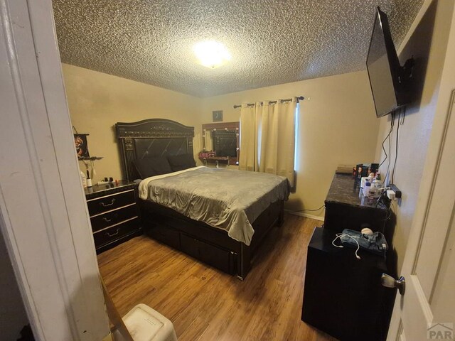 bedroom with a textured ceiling and wood finished floors