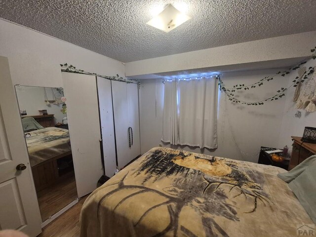 bedroom featuring a textured ceiling, a closet, and wood finished floors