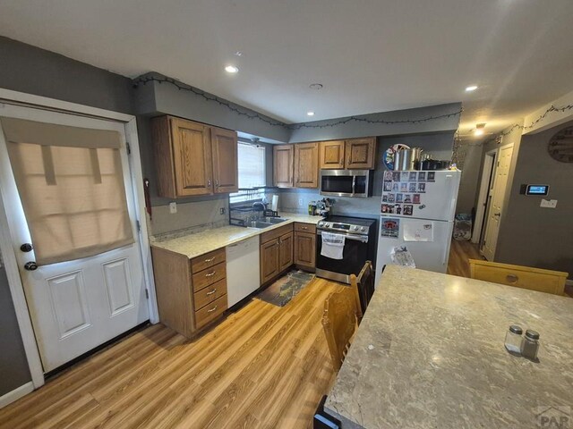 kitchen featuring light wood finished floors, light countertops, appliances with stainless steel finishes, and brown cabinetry