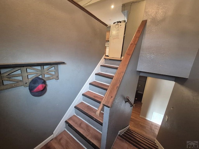 staircase featuring baseboards and wood finished floors