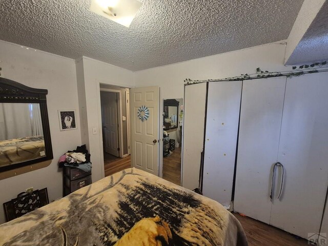 bedroom featuring a textured ceiling, dark wood-type flooring, and a closet