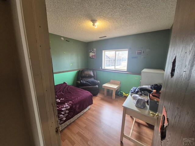 bedroom featuring a textured ceiling, light wood-type flooring, and visible vents