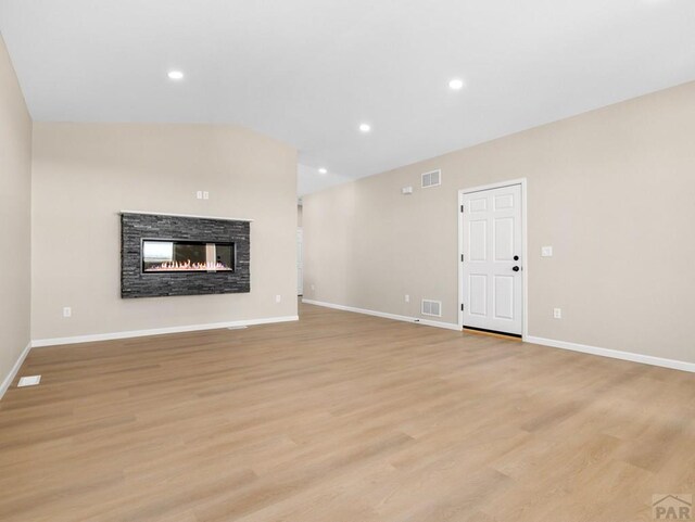 unfurnished living room with light wood-type flooring, visible vents, a fireplace, and baseboards