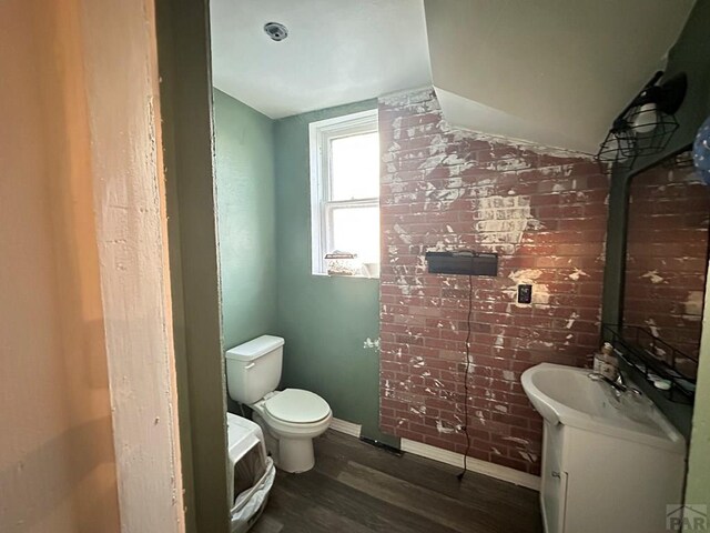 bathroom with baseboards, toilet, wood finished floors, vaulted ceiling, and vanity