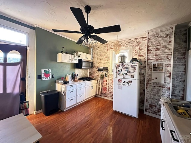 kitchen with dark wood-style flooring, white cabinetry, light countertops, freestanding refrigerator, and stainless steel microwave