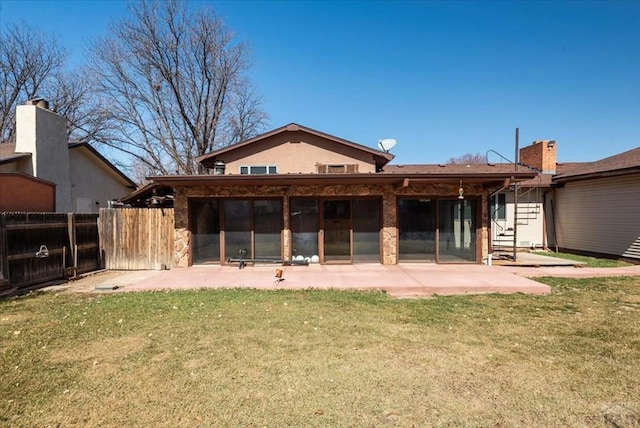 rear view of property featuring a patio, a lawn, and fence