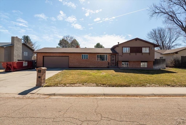 tri-level home with a garage, a front yard, brick siding, and driveway