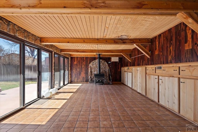 unfurnished sunroom featuring beam ceiling, a wood stove, and wood ceiling