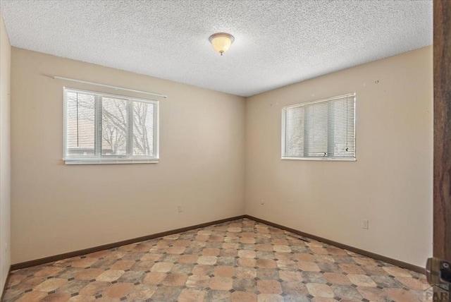 unfurnished room with tile patterned floors, baseboards, and a textured ceiling