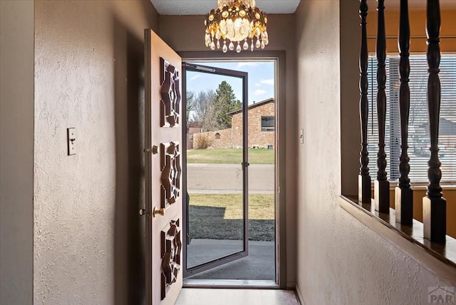 entryway featuring an inviting chandelier and a textured wall