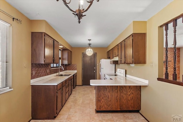 kitchen with white appliances, a peninsula, a sink, light countertops, and backsplash