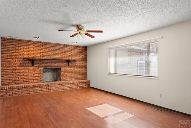 unfurnished living room featuring baseboards, a textured ceiling, wood finished floors, and a ceiling fan