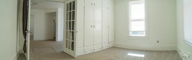unfurnished bedroom with light carpet, a closet, and baseboards