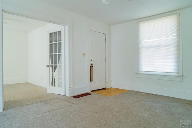 carpeted empty room featuring visible vents