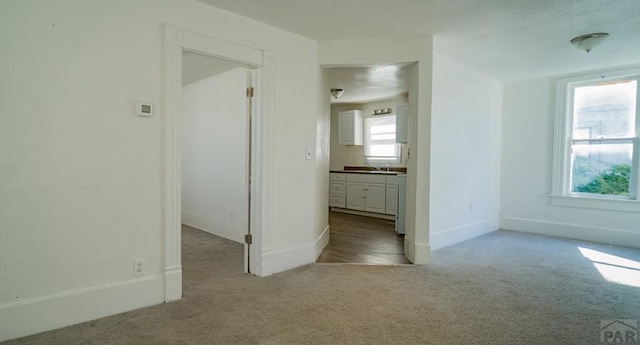 unfurnished bedroom featuring a sink, carpet floors, and baseboards