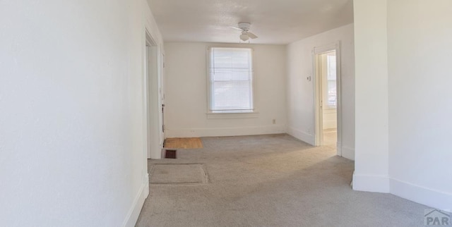 empty room with carpet floors, baseboards, and a ceiling fan