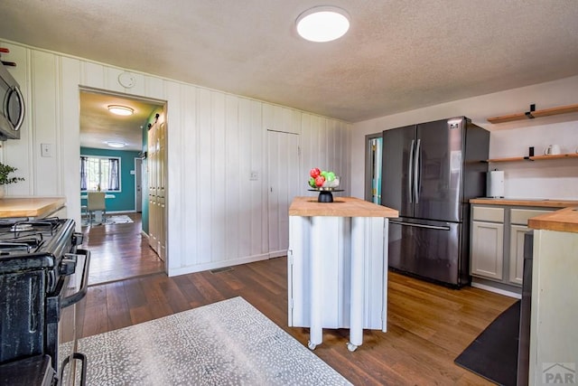 1232 Spruce St, Pueblo, CO 81004 - kitchen featuring butcher block countertops, appliances with stainless steel finishes, dark wood finished floors, a textured ceiling, and open shelves