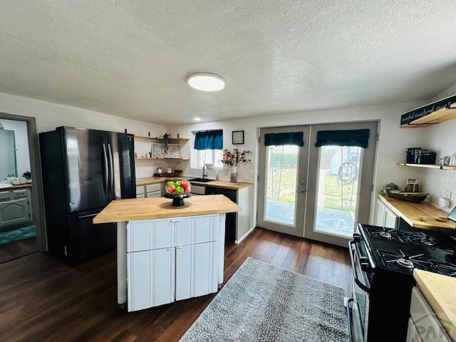 1232 Spruce St, Pueblo, CO 81004 - kitchen with wood counters, open shelves, black appliances, french doors, and a textured ceiling