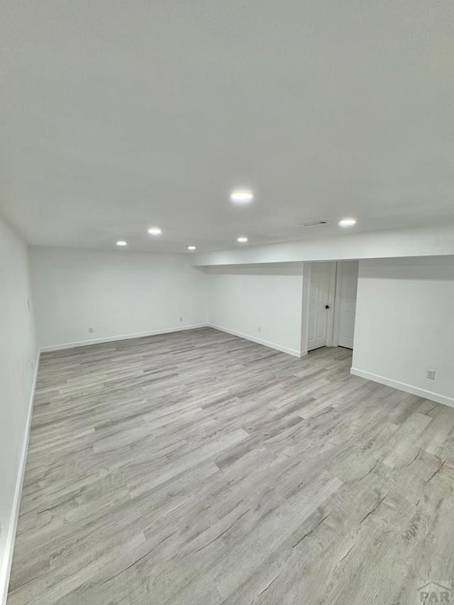 finished below grade area with light wood finished floors, baseboards, and recessed lighting