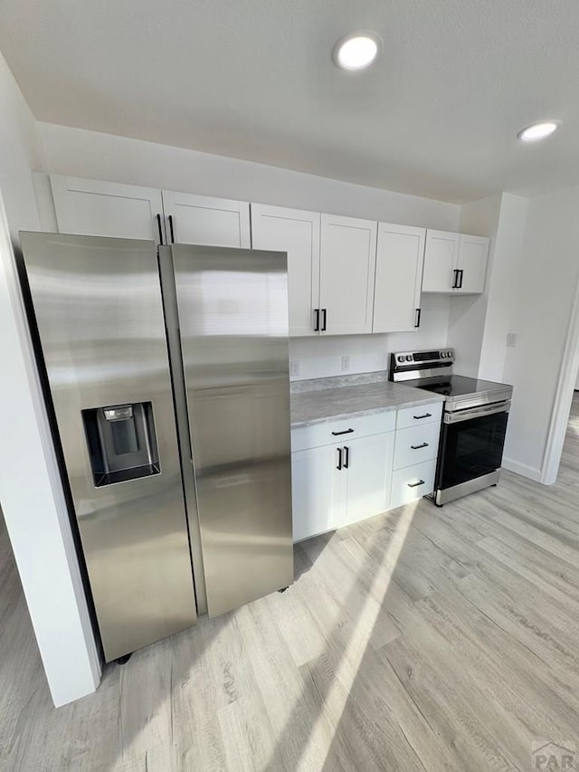 kitchen featuring white cabinets, stainless steel appliances, light countertops, light wood-style floors, and recessed lighting