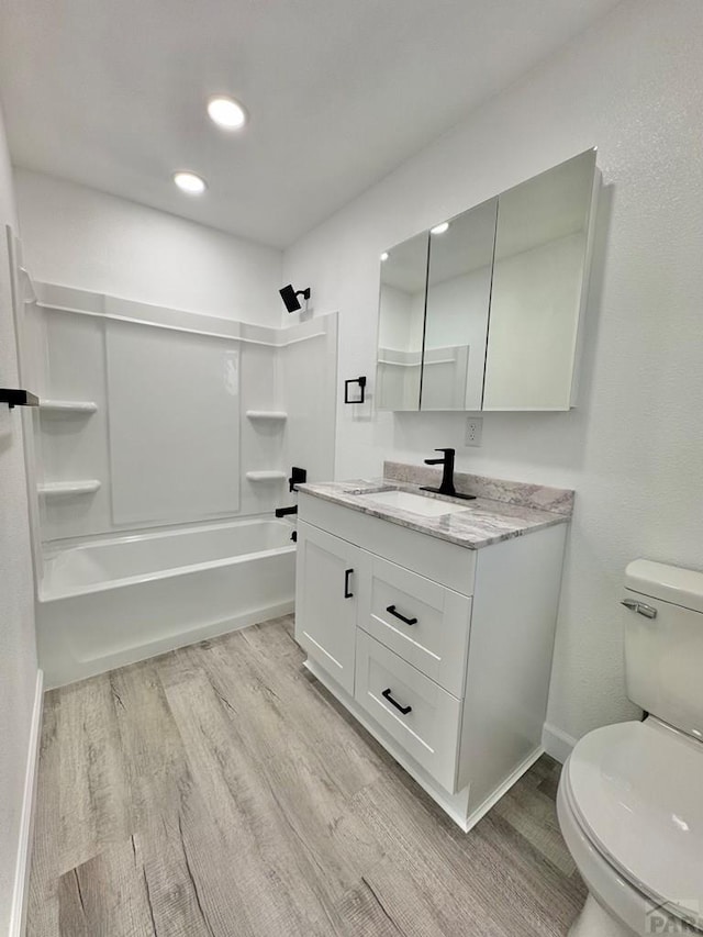 bathroom featuring shower / bathing tub combination, toilet, vanity, wood finished floors, and baseboards