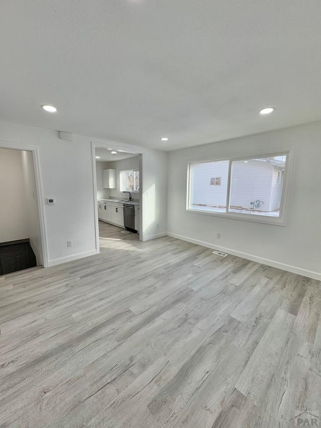 unfurnished living room featuring light wood-type flooring, baseboards, and recessed lighting