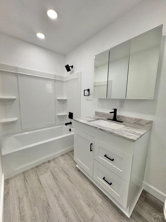 bathroom featuring recessed lighting, shower / bath combination, wood finished floors, vanity, and baseboards