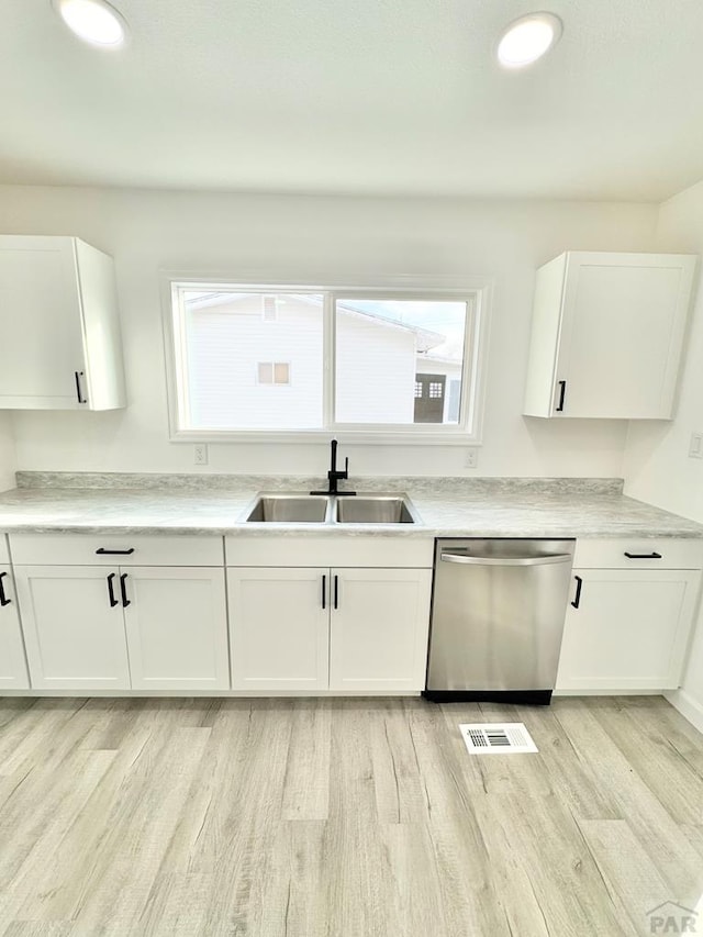 kitchen featuring dishwasher, light countertops, light wood-type flooring, white cabinetry, and a sink