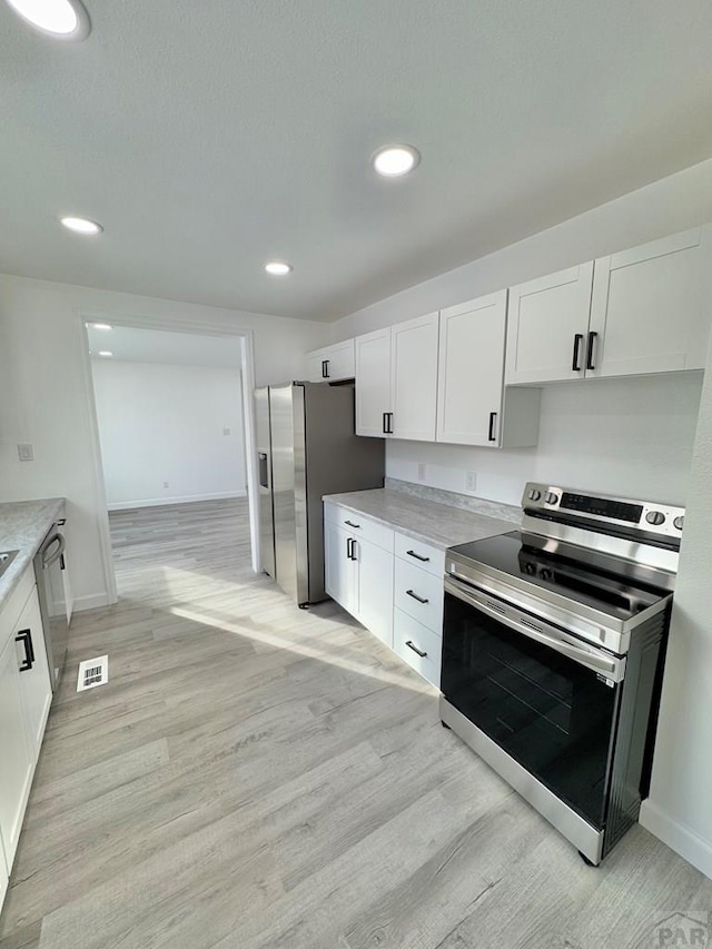 kitchen featuring stainless steel appliances, light countertops, white cabinetry, and light wood-style floors