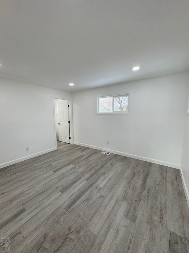 empty room featuring recessed lighting, wood finished floors, and baseboards