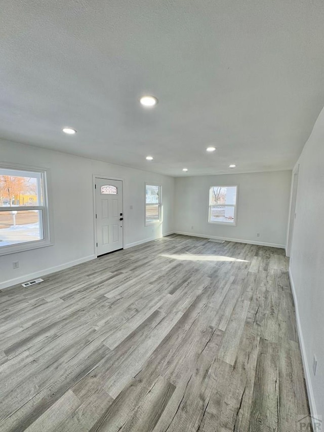 unfurnished living room featuring recessed lighting, light wood-type flooring, visible vents, and baseboards