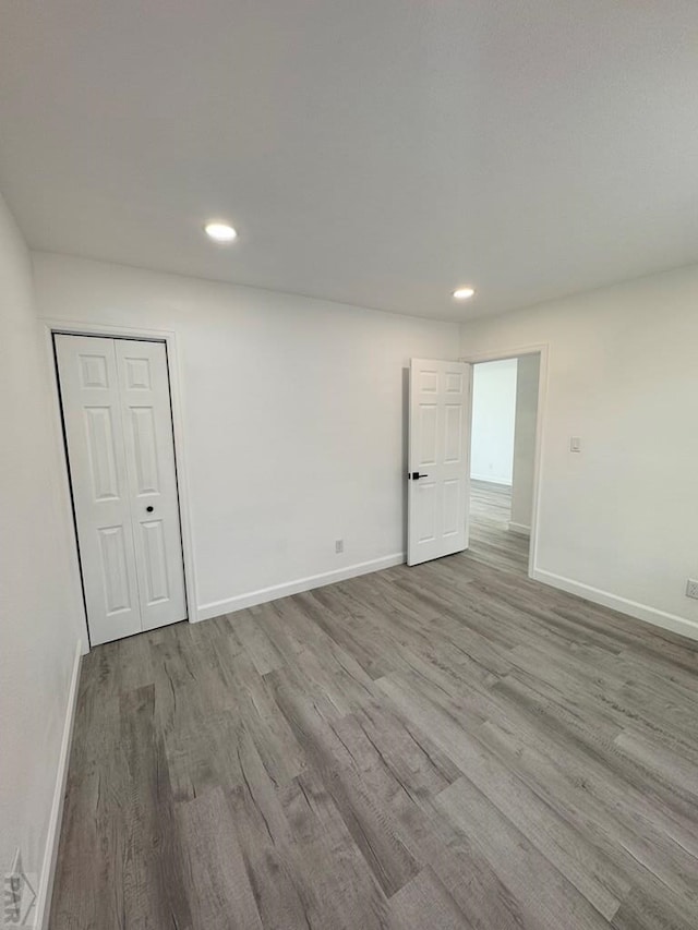 spare room with recessed lighting, baseboards, and wood finished floors