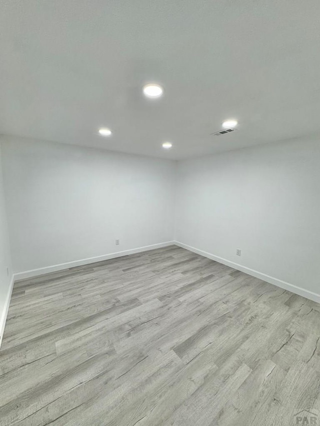 below grade area featuring light wood-style flooring, visible vents, and baseboards