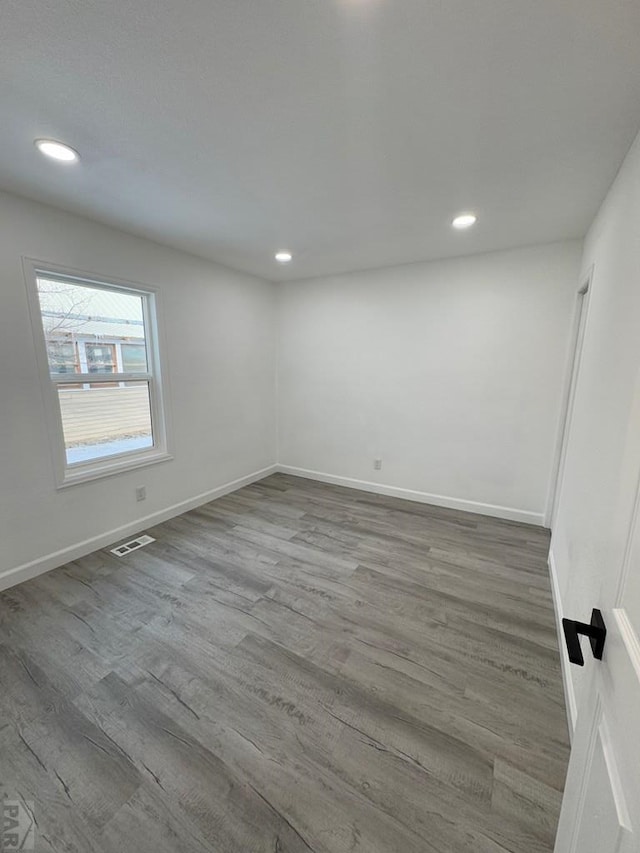 empty room featuring baseboards, visible vents, wood finished floors, and recessed lighting