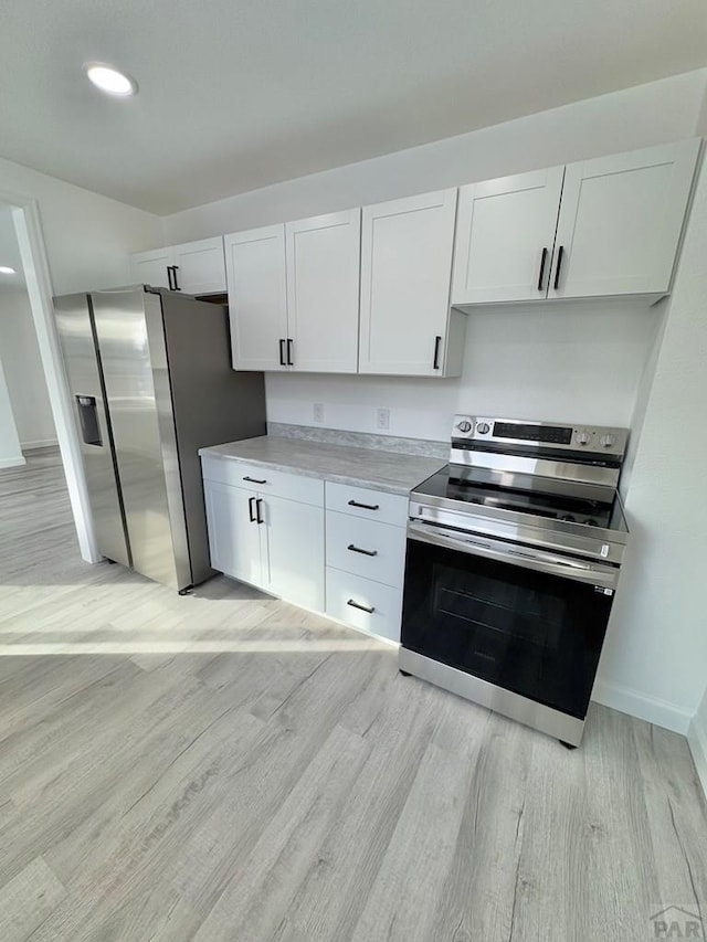 kitchen featuring baseboards, stainless steel appliances, light countertops, light wood-type flooring, and white cabinetry