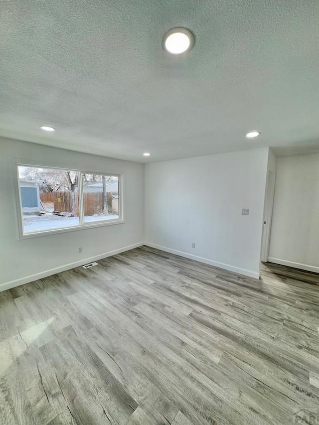 spare room with recessed lighting, visible vents, baseboards, and wood finished floors