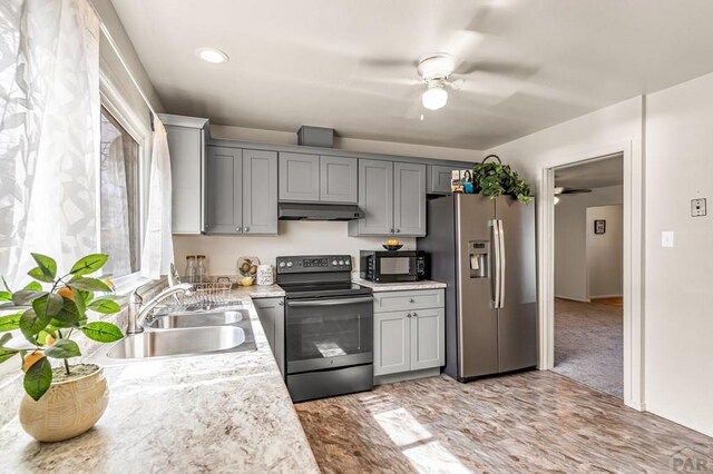 kitchen with gray cabinets, a sink, electric range oven, under cabinet range hood, and stainless steel fridge